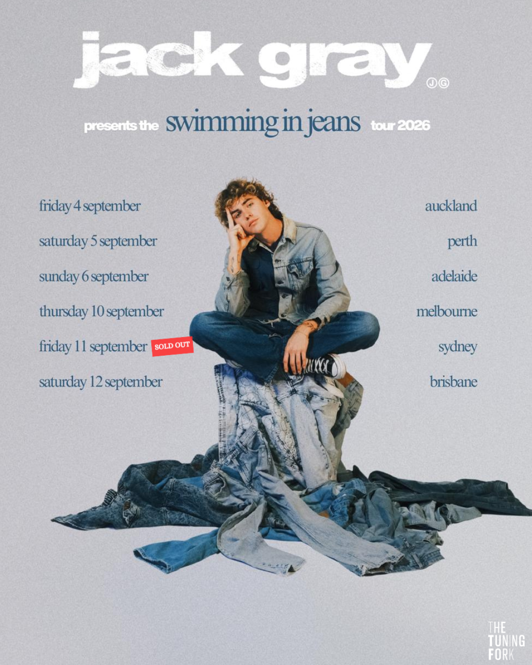Tour poster for Jack Gray Swimming In Jeans Tour 2026, showing the singer sitting cross-legged on a pile of denim with Australia and NZ dates.